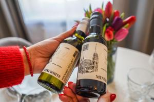 deux mains tenant deux bouteilles de vin sur une table dans l'établissement BelVie Residence, à Vienne