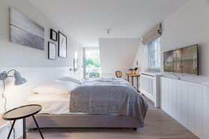 ein weißes Schlafzimmer mit einem Bett und einem Tisch in der Unterkunft Haus Tofino in Wyk auf Föhr