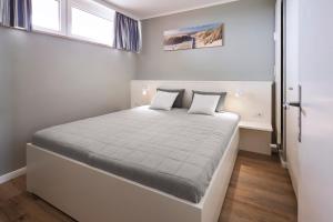 1 dormitorio con 1 cama blanca grande y 2 almohadas en Haus Uthlande 39, en Wyk auf Föhr