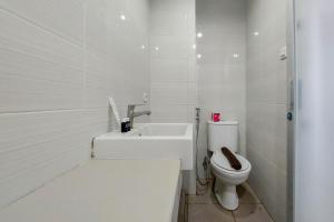 uma casa de banho branca com um WC e um lavatório em Brand New and Nice Studio at Skyview Medan Apartment By Travelio em Sunggal