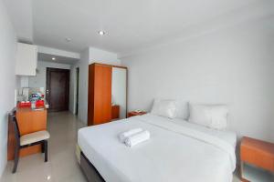 um quarto com uma grande cama branca e uma cadeira em Brand New and Nice Studio at Skyview Medan Apartment By Travelio em Sunggal