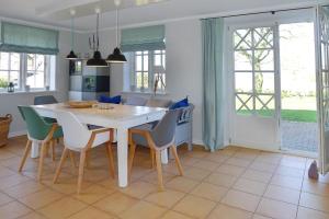 Alkersum的住宿－Haus Weitblick，厨房以及带白色桌椅的用餐室。