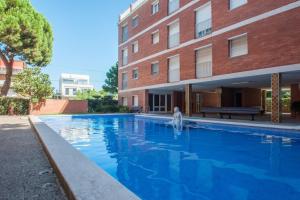 una grande piscina blu accanto a un edificio di BEACHFRONT APARTMENT Castelldefels a Castelldefels