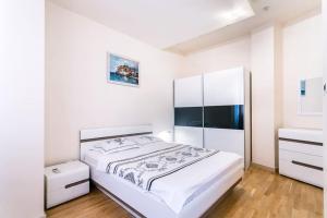a white bedroom with a bed and a dresser at Stylish spacious apartment near the sea in Budva