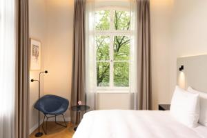 ein Schlafzimmer mit einem Bett, einem Fenster und einem Stuhl in der Unterkunft ESPLANADE Saarbrücken in Saarbrücken