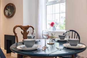 a dining room table with plates and wine glasses at 1 Phoenix Cottages, 403 High Street, Cheltenham in Cheltenham