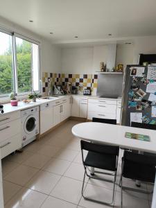 a white kitchen with a table and a refrigerator at Chambre d'hôte proche de la nature in Lamorlaye