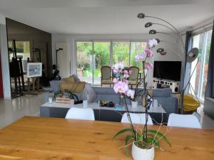 ein Wohnzimmer mit einem Sofa und einem Tisch mit Blumen in der Unterkunft Chambre d'hôte proche de la nature in Lamorlaye