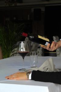 una persona vertiendo una botella de vino en una copa en Hotel Opera Jaz en Budva