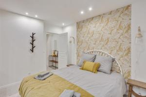 a white bedroom with a bed with a yellow pillow at 143 Suite La Française Superbe Appartement à Paris in Paris