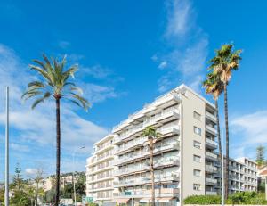 a tall white apartment building with palm trees at COSY STUDIO - Résidence front de mer - Menton in Menton