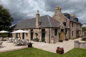 un gran edificio de piedra con mesas y sillas en un patio en Kildrummy Inn, en Kildrummy