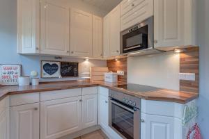 a kitchen with white cabinets and a stove top oven at Hüs Leen in Hedehusum