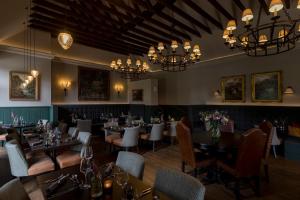 a dining room with tables and chairs and chandeliers at Kildrummy Inn in Kildrummy