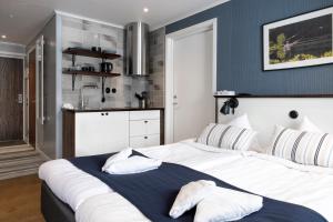 a bedroom with a large white bed and a kitchen at Lakelodge in Karlskoga