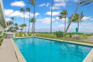 a large blue swimming pool with palm trees in the background at Beautiful Beachfront Condo in Laie