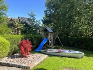 a playground with a slide and a boat in a yard at Nordsee Ferienwohnung 9 Personen in Wangerland +24 photos