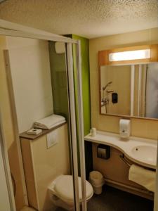 bagno con servizi igienici, lavandino e specchio di Hotel Inn Design Montluçon a Montluçon