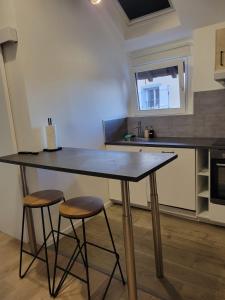 a kitchen with a large table and two stools at Appartement COSY proche de Paris in Chambourcy
