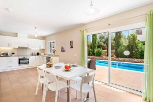 Una cocina y un comedor con una mesa y sillas blancas. en Sa Lluna Galdana, en Cala Galdana