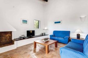 Una sala de estar con un sofá azul y un televisor. en Villa Bini Blanca, en Binibeca