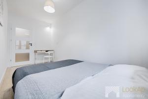a white bedroom with a bed and a desk at Diasfera II by LookAp in Łódź