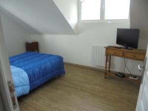 a bedroom with a bed and a desk with a television at gîte des étangs in Nesle-Normandeuse
