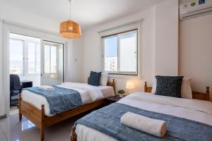 two beds in a room with windows at Jayde 2-Bedroom Apartment in Larnaca in Larnaca