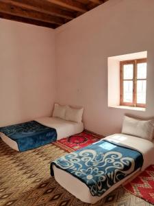 two beds sitting in a room with a window at Gite chez Ali Agouti Maison Berbère in Idoukaln