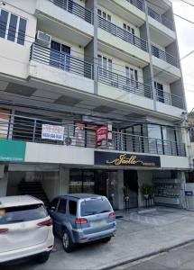 two cars parked in front of a building at Jaelle Residences Hotel - Downtown in Lucena