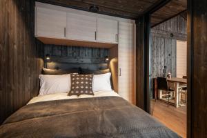1 dormitorio con 1 cama grande y pared de madera en Kikut Alpin Lodge 2302, en Geilo