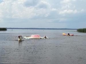 een groep mensen in het water op boten bij Kempings Ezerpriedes in Burtnieki