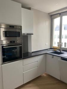 a kitchen with white cabinets and stainless steel appliances at Bel Appartement 2 pièces à Neuilly Porte Maillot ! in Neuilly-sur-Seine