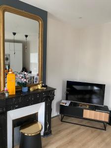 een woonkamer met een spiegel en een open haard bij Bel Appartement 2 pièces à Neuilly Porte Maillot ! in Neuilly-sur-Seine