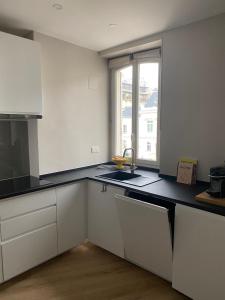 een keuken met witte kasten, een wastafel en een raam bij Bel Appartement 2 pièces à Neuilly Porte Maillot ! in Neuilly-sur-Seine