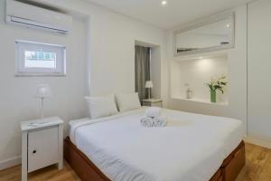 Un dormitorio blanco con una cama grande con dos cajas. en Pátios das Marias, en Setúbal