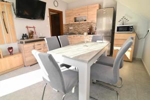 uma cozinha com uma mesa com cadeiras e um frigorífico em Vár-Lak Apartman em Sümeg
