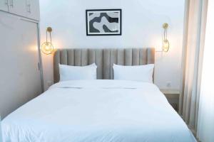 1 dormitorio con 1 cama grande con sábanas blancas en Nzuri Nest -Queen en Kigali