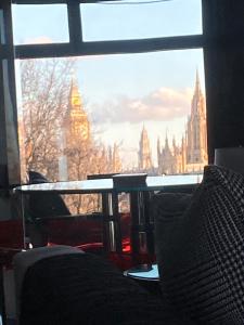 a view of london from a window with a table at Luxury Designer Apartment River view of Parliament Westminster Big Ben. in London