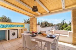 a patio with a table and chairs and a kitchen at Villa Dei Lidi - HomeSalento com in Torre San Giovanni Ugento