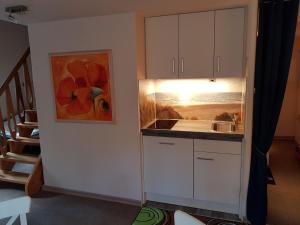 una cocina con armarios blancos y una pintura en la pared en Appartment Holiday, en Scharbeutz