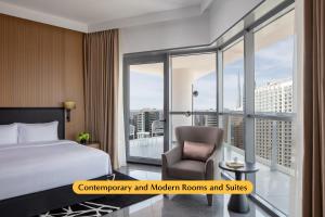 The First Collection Business Bay في دبي: غرفة نوم بسرير وكرسي ونافذة