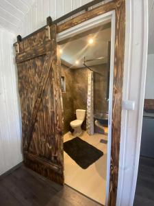 a large wooden door in a bathroom with a toilet at DarWik Domki Letniskowe in Bukowo Morskie