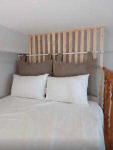 1 cama con almohadas blancas y cabecero de madera en Odyssey's Feats en Plati