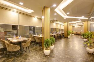 a restaurant with tables and chairs and potted plants at Hotel Park Tree - IGI Airport A UNIT Of PRITHVI PALACE in New Delhi