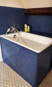 y baño con bañera y azulejos azules. en Maison dans parc privé (JO 2024), en La Celle-Saint-Cloud