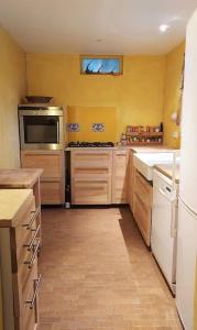 cocina con paredes amarillas y cocina con nevera en Maison dans parc privé (JO 2024), en La Celle-Saint-Cloud