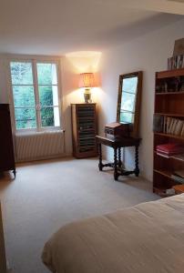 1 dormitorio con cama, espejo y escritorio en Maison dans parc privé (JO 2024), en La Celle-Saint-Cloud
