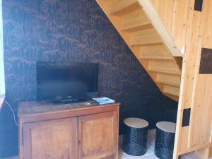 a living room with a tv and two stools at Chambres d'Hôtes Grange Carrée in Saint-Rémy