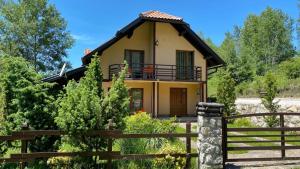茲拉蒂博爾的住宿－Vikendica Životić，前面有围栏的小黄色房子
